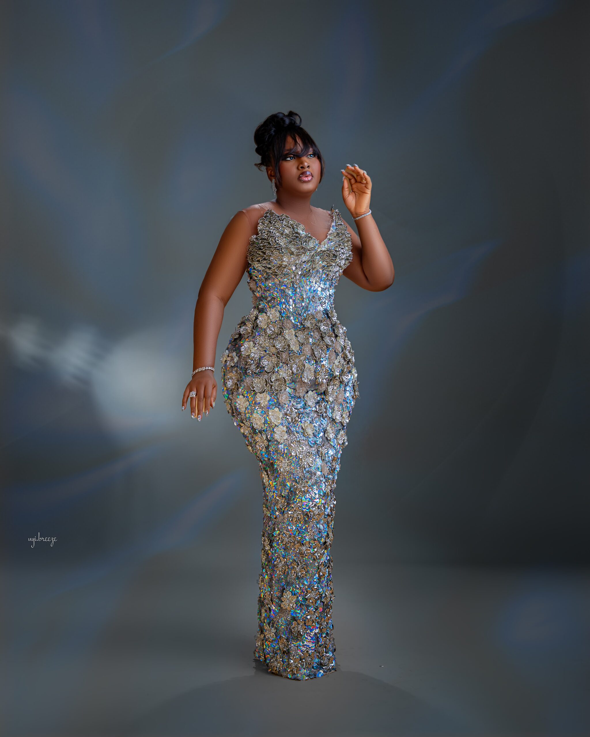 Mo Bimpe posing in a fitted silver metallic gown for her triplets thanksgiving reception in Lekki Lagos.