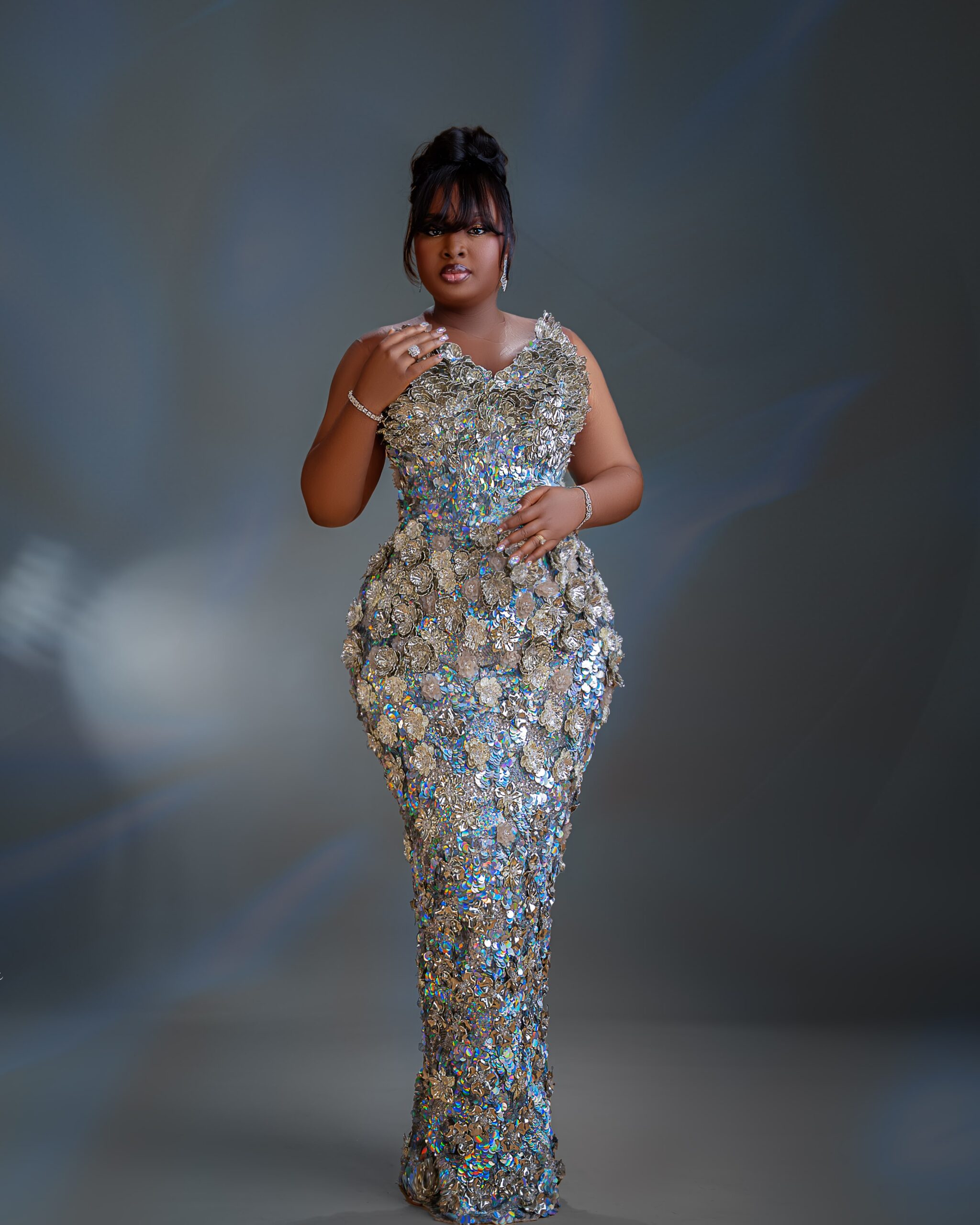 Mo Bimpe wearing a structured silver dress with 3D floral appliques at her triplets thanksgiving party.