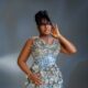 Mo Bimpe showing her topknot hair, glossy glam, and metallic sequin gown details.