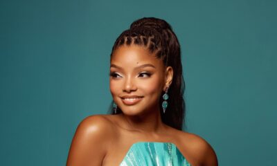 Halle Bailey posing in a strapless metallic teal Valdrin Sahiti dress with shell pleated bust.