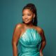 Halle Bailey posing in a strapless metallic teal Valdrin Sahiti dress with shell pleated bust.