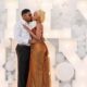 Diana Eneje kissing her fiancé in front of white balloons and illuminated marquee letters.