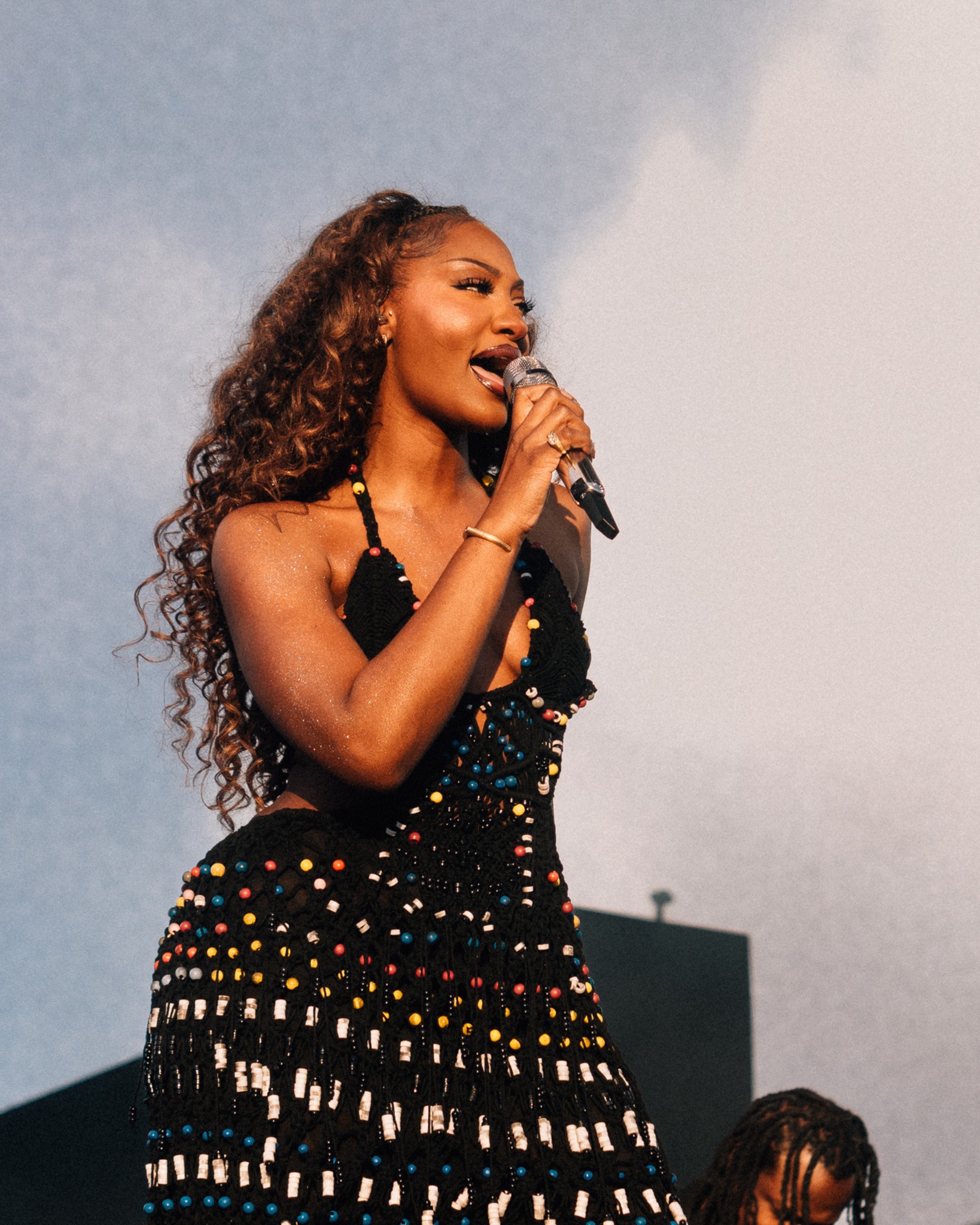 Tems wearing a black crochet cut-out dress during her London festival performance.