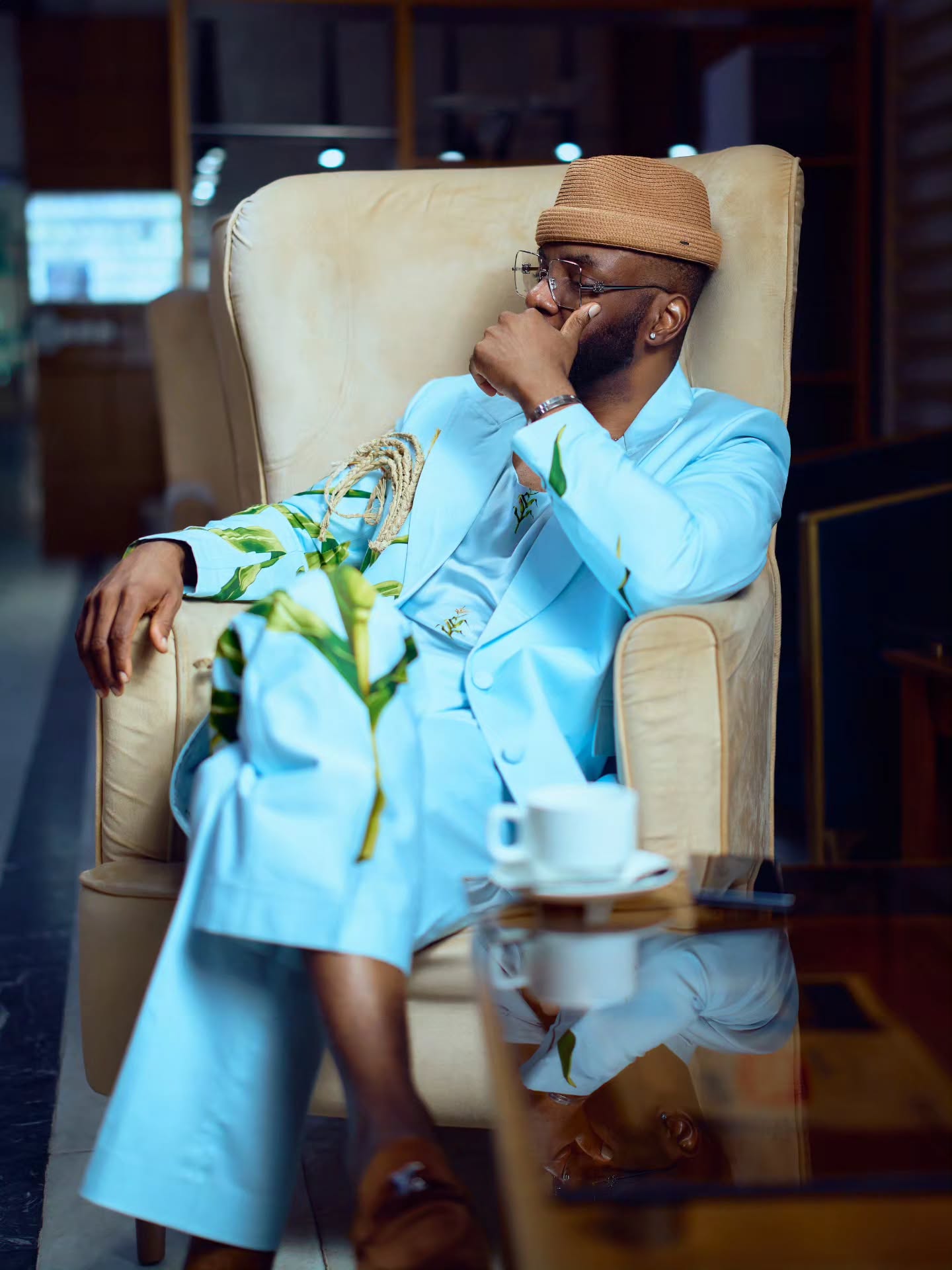 Ebuka Obi-Uchendu wearing a sky-blue suit, brown straw hat, and silver chain necklace.