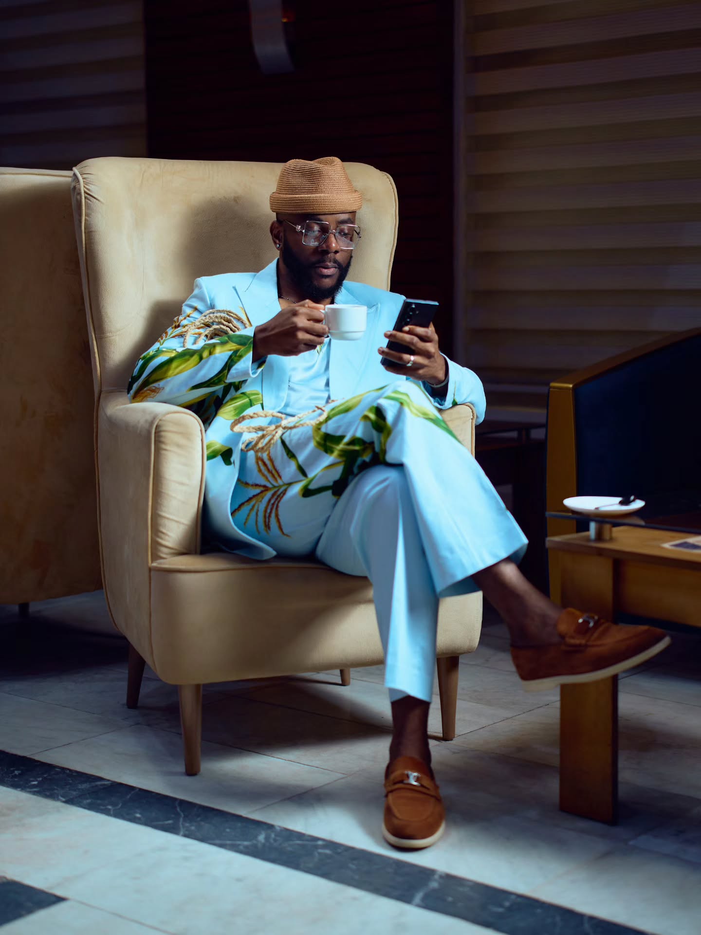 Ebuka Obi-Uchendu wearing a sky-blue Lisa Folawiyo suit with maize embroidery and a brown straw hat.