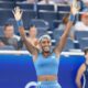 Coco Gauff smiling with both hands raised to applaud the court crowd