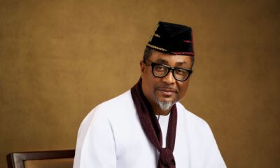 Tony Umez wearing a black embroidered cap, white tunic, and maroon scarf.