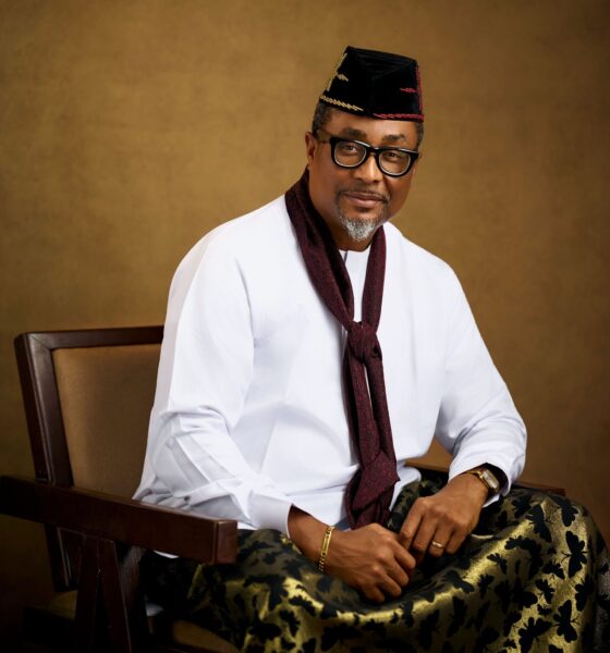 Tony Umez wearing a black embroidered cap, white tunic, and maroon scarf.