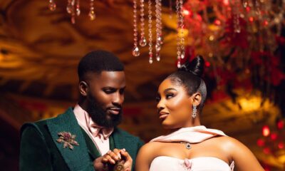 Akin Faminu holding hands with Kiky Festus, featuring his floral brooch and her embellished blush pink gown.