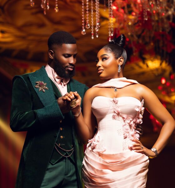 Akin Faminu holding hands with Kiky Festus, featuring his floral brooch and her embellished blush pink gown.