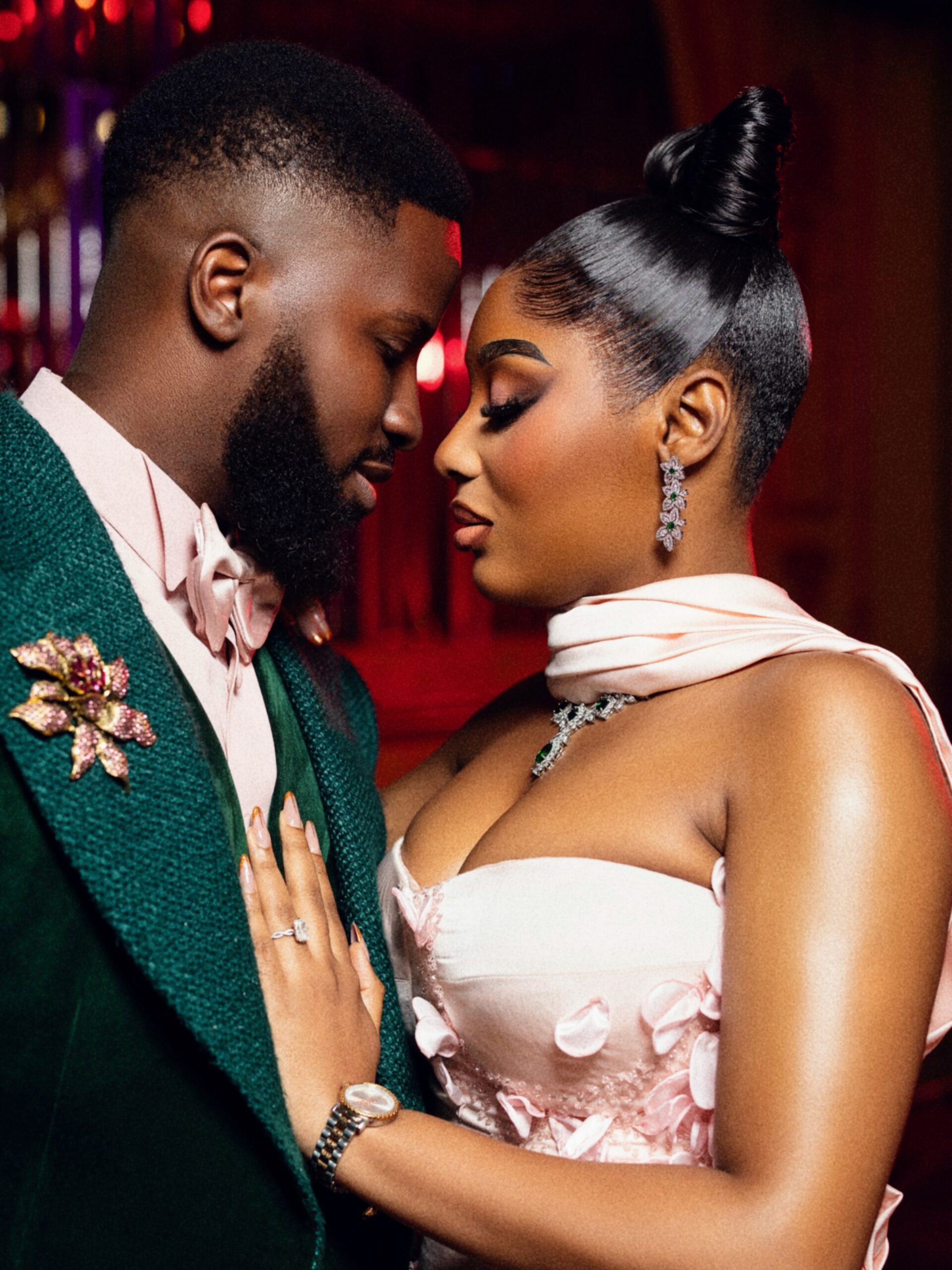 Akin Faminu in a Deji and Kola green velvet suit leaning towards Kiky Festus wearing a Firstlady blush pink corset gown.