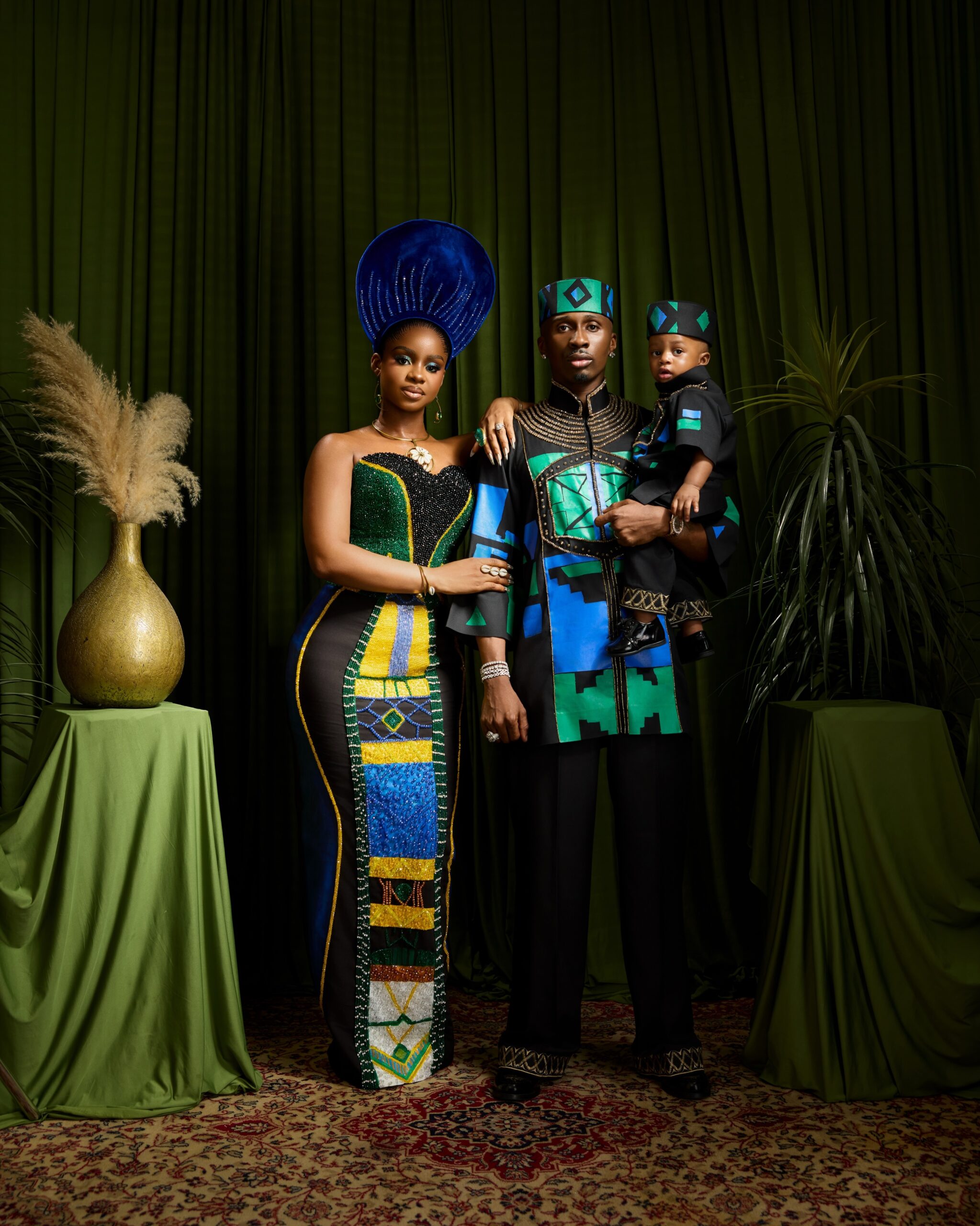 Priscilla Ojo, Juma Jux holding baby Rakeem in matching black and teal outfits.