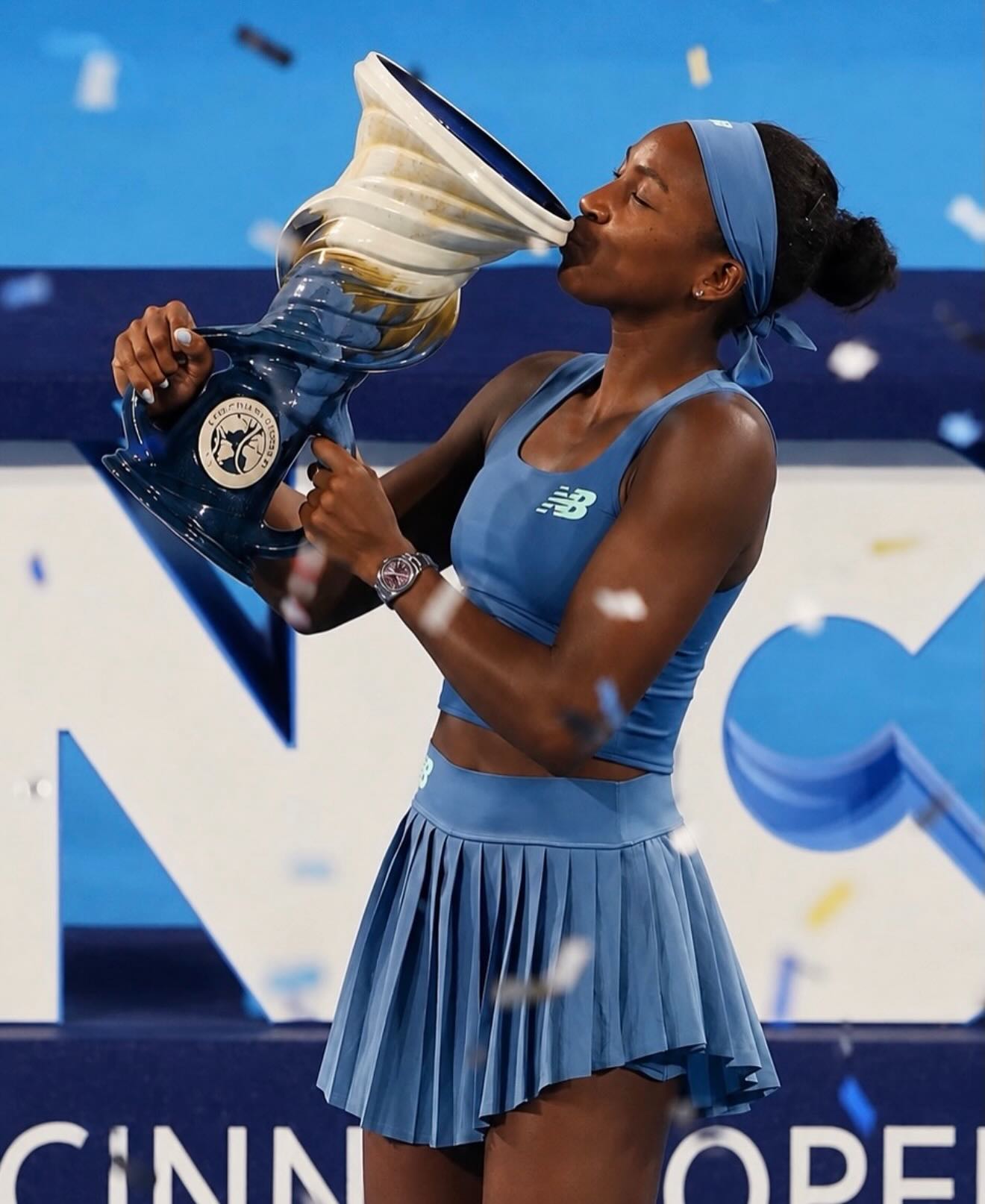Coco Gauff kissing the Rookwood Cup trophy under falling confetti at the 2026 Cincinnati Open.