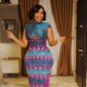 Joselyn Dumas standing in a fitted blue and pink Kente Kiosk gown with fringe hemline.