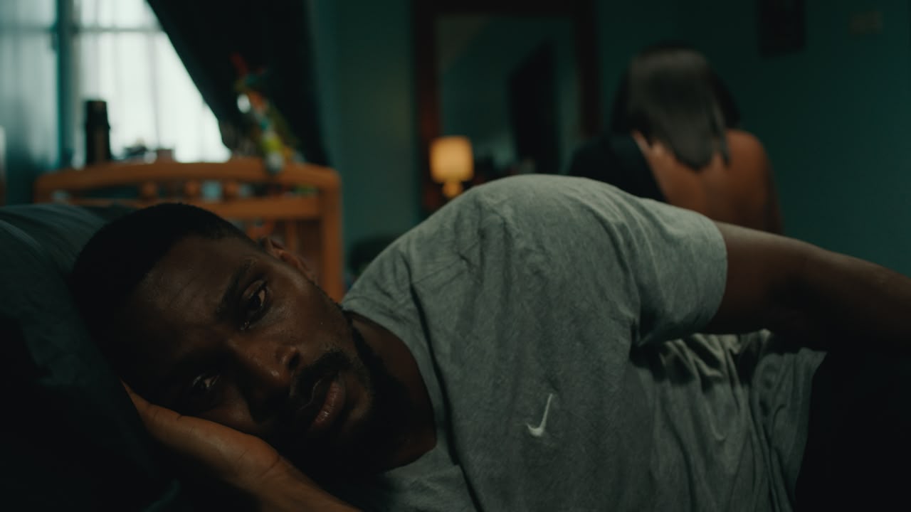 Tobi Bakre as Tola lying awake on a pillow in the bedroom in Before We Fall Asleep.