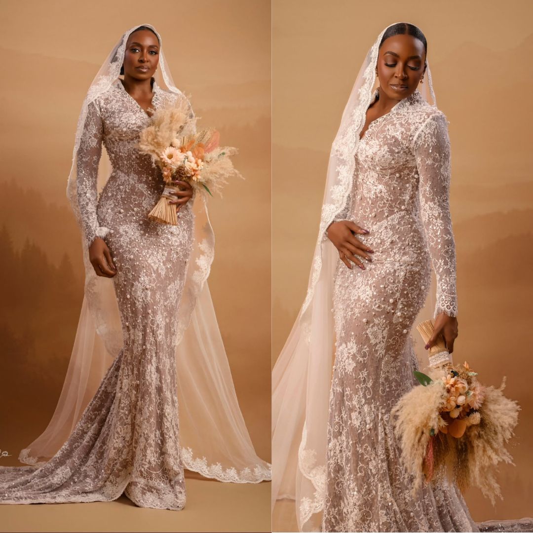 Kate Henshaw in a fitted white lace bridal gown with a matching lace veil holding a dried floral bouquet.