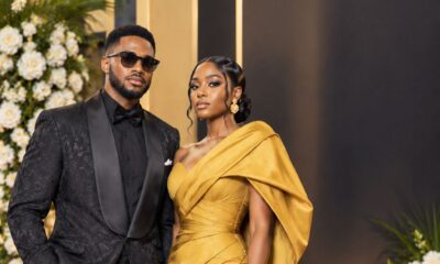 Couple on the red carpet wearing a mustard gold one-shoulder couture gown and a textured black tux for the BN 20 Gala High Fashion Icon dress code.