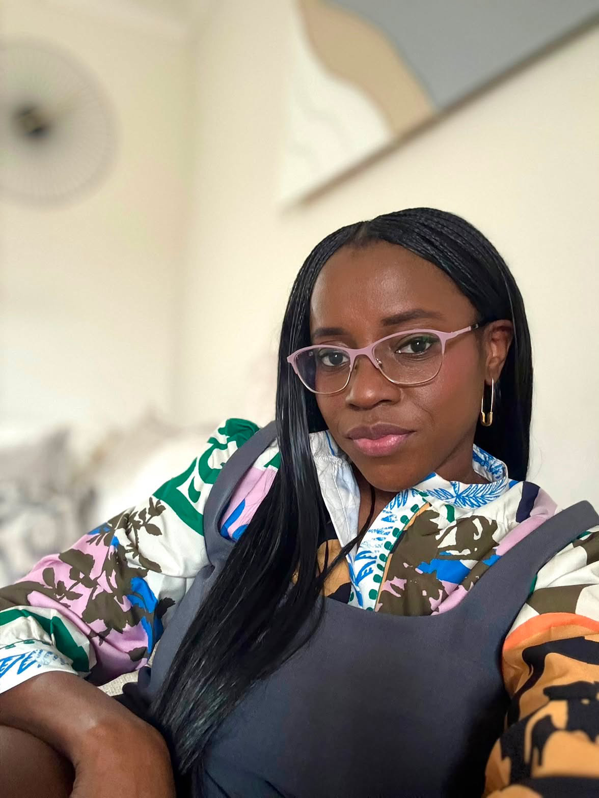 Former BellaNaija columnist Mrs Kush wearing pink glasses and a patterned top.