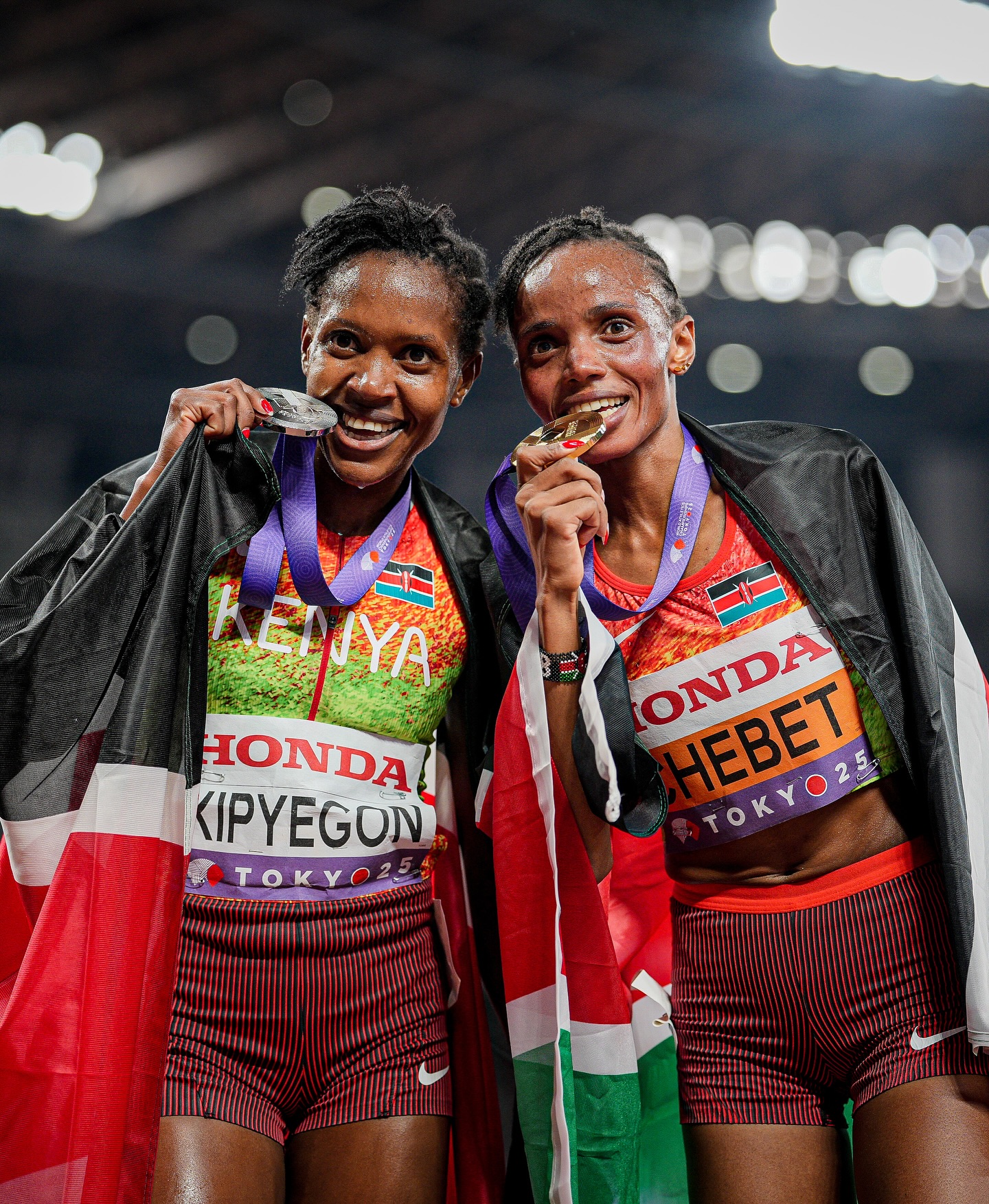 Faith Kipyegon holding silver medal and Beatrice Chebet holding gold medal wrapped in Kenyan flags at Tokyo 25 World Athletics Championships