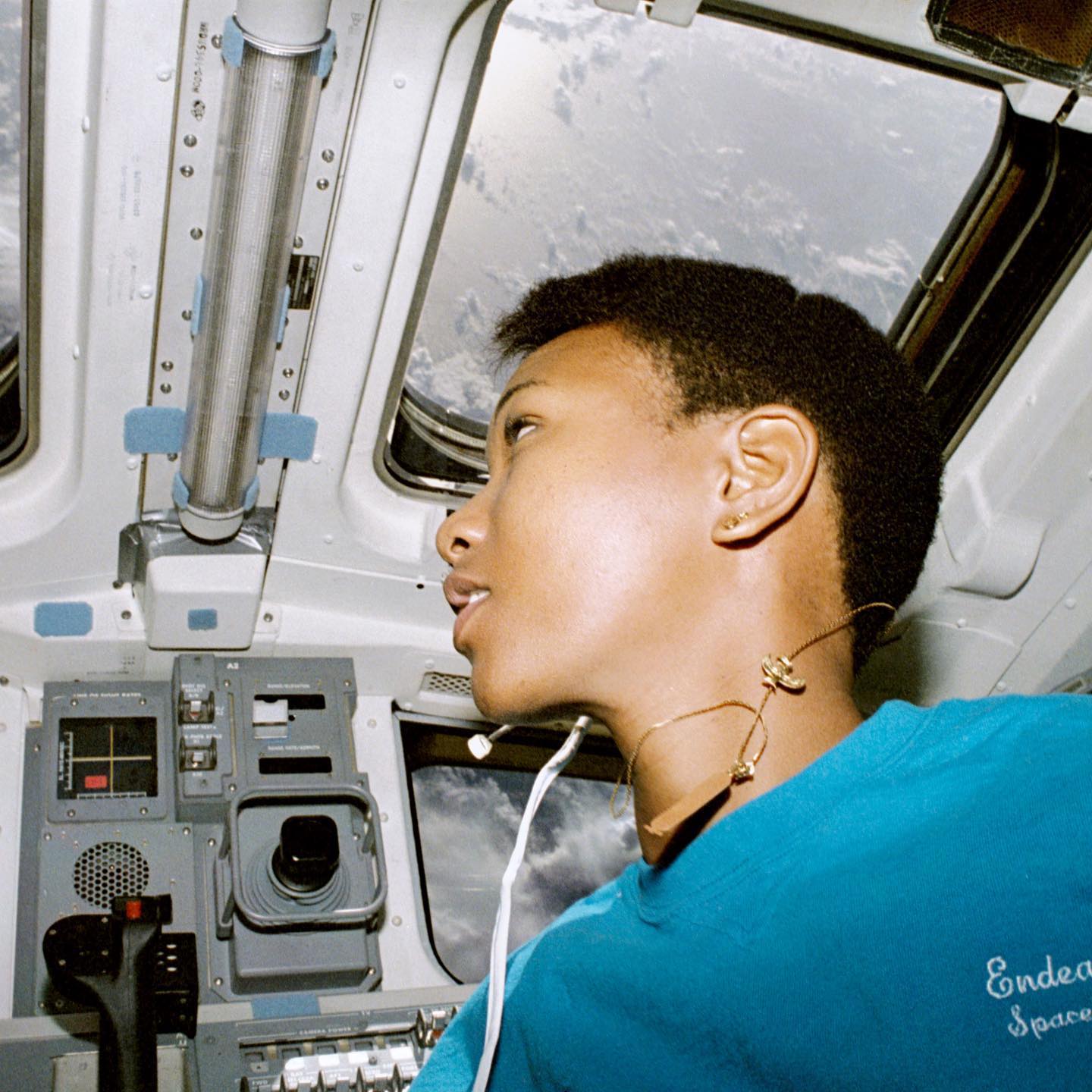 Dr Mae Jemison inside the Space Shuttle Endeavour flight deck looking towards the window with Earth in the background.