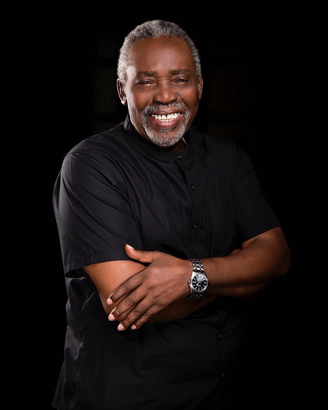 Late veteran Nollywood actor Oludotun Baiyewu Jacobs smiling in a black shirt with arms crossed.