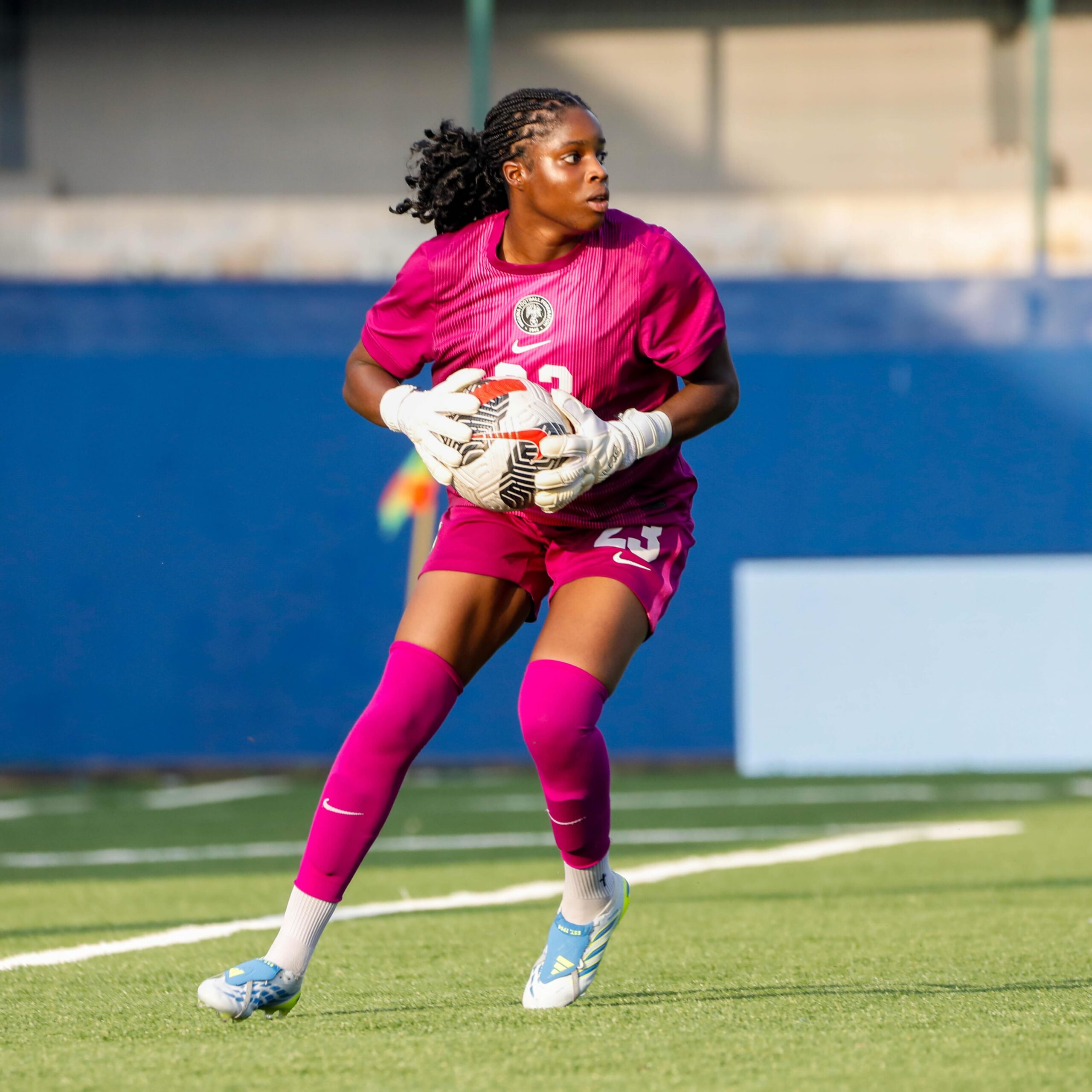 Comfort Erhabor in a pink Nigeria goalkeeper kit clutching a football during her international debut against Cameroon.