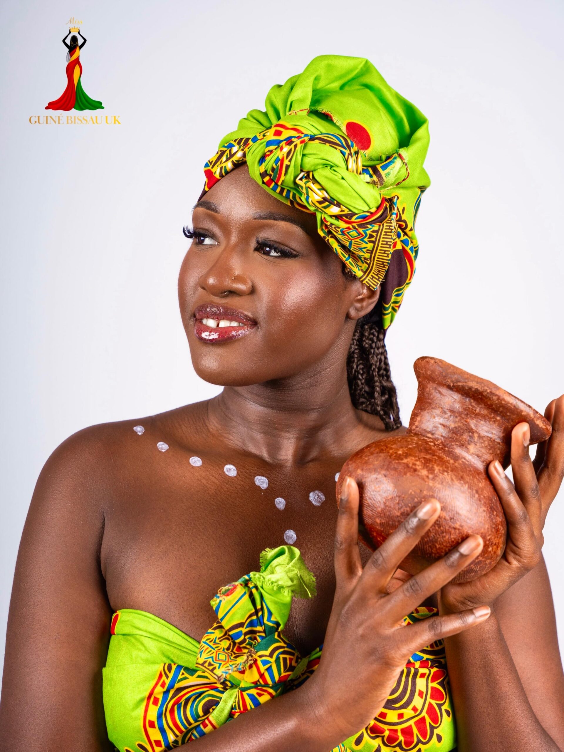 Gisela Sal holding a clay pot while wearing a bright green headwrap for Miss Guiné-Bissau UK 2026