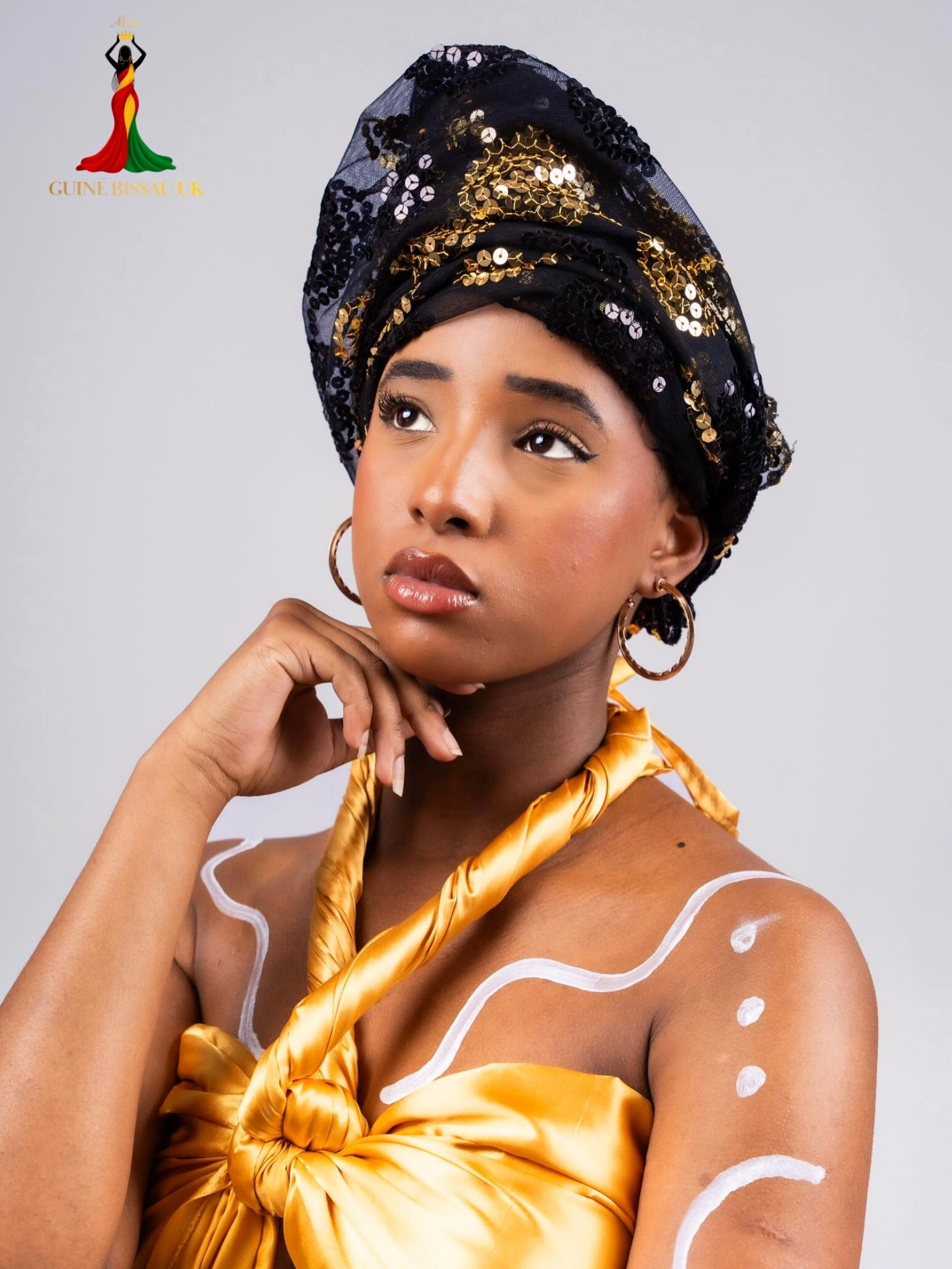 Maísa Spencer wearing a black sequined headwrap and gold satin drape for Miss Guiné-Bissau UK 2026