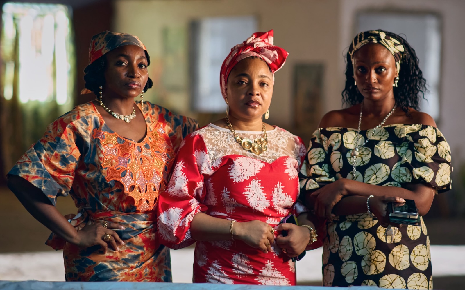 Omowunmi Dada, Linda Ejiofor-Suleiman, and Scarlet Gomez dressed in traditional patterned outfits for Black Market