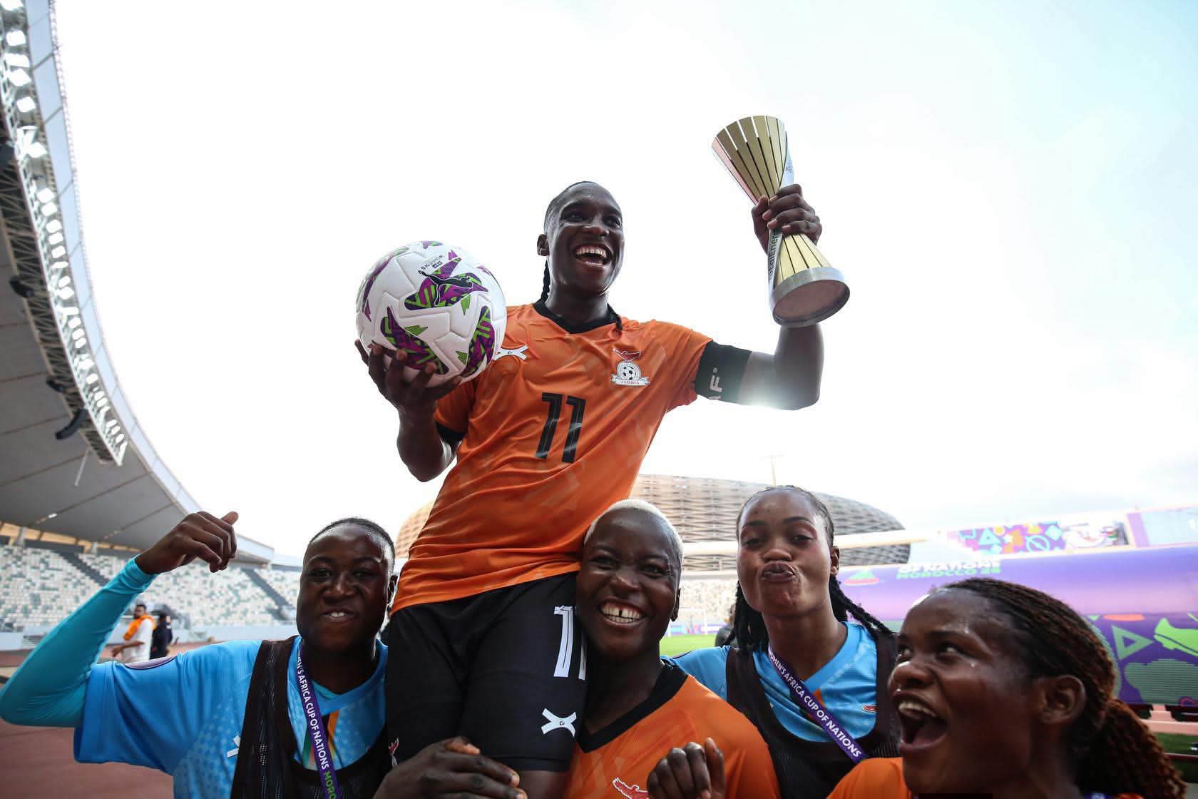 Barbra Banda lifted on the shoulders of her Zambia teammates while holding the WAFCON trophy and match ball inside the stadium.