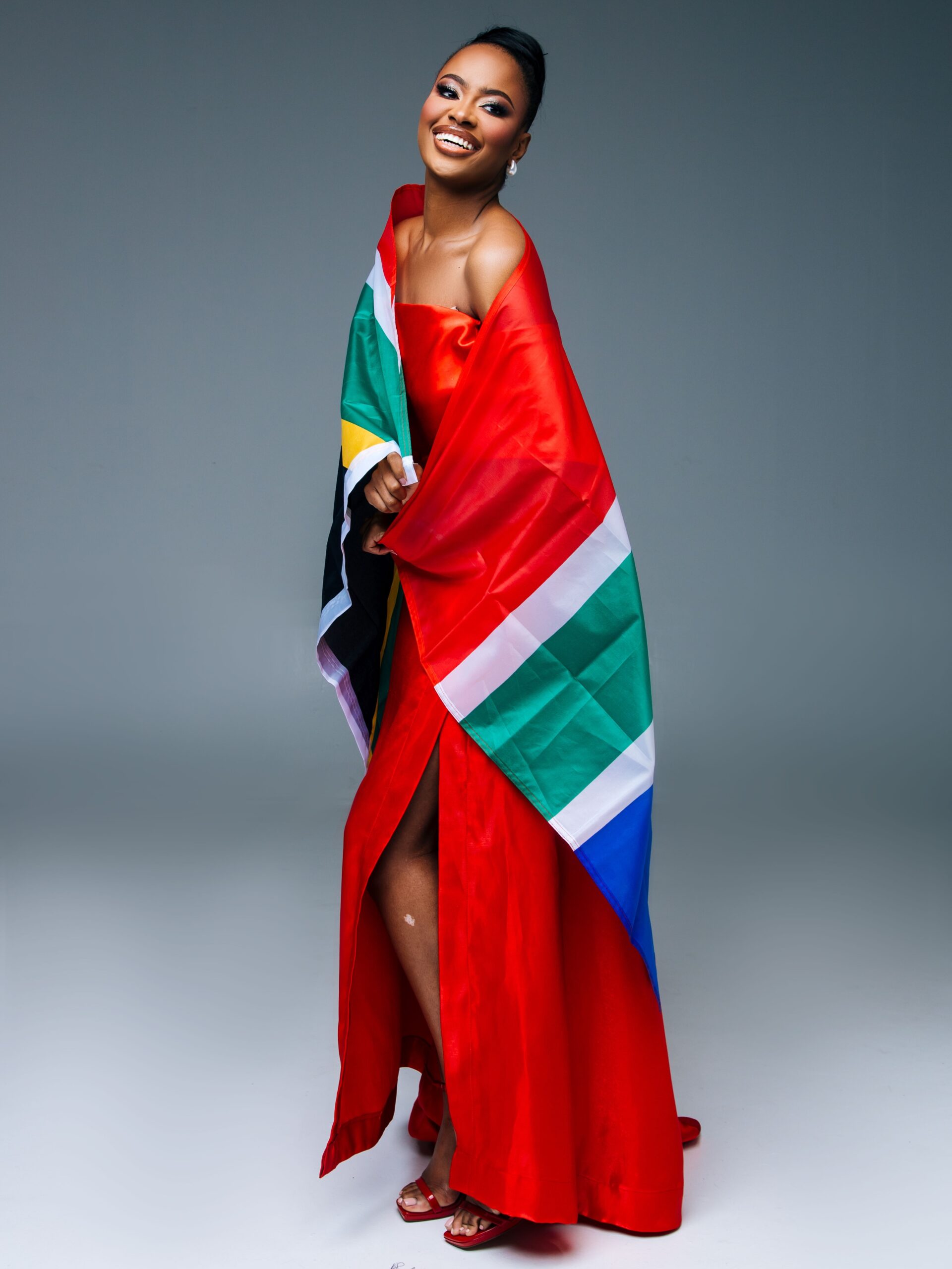 Romanda Hombir wearing a red gown draped with the South African flag ahead of Miss World 2026.
