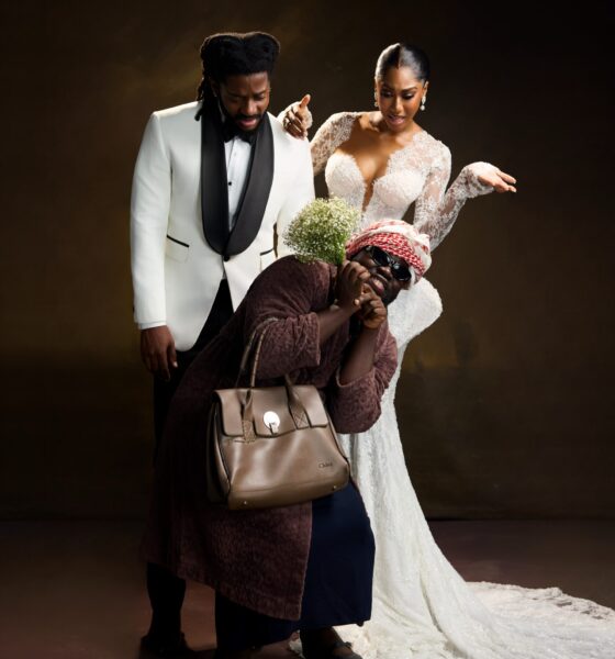 Laura Ajayi in a lace wedding gown and David Uruka in a white tuxedo standing behind Folagade Banks as Mama Deola