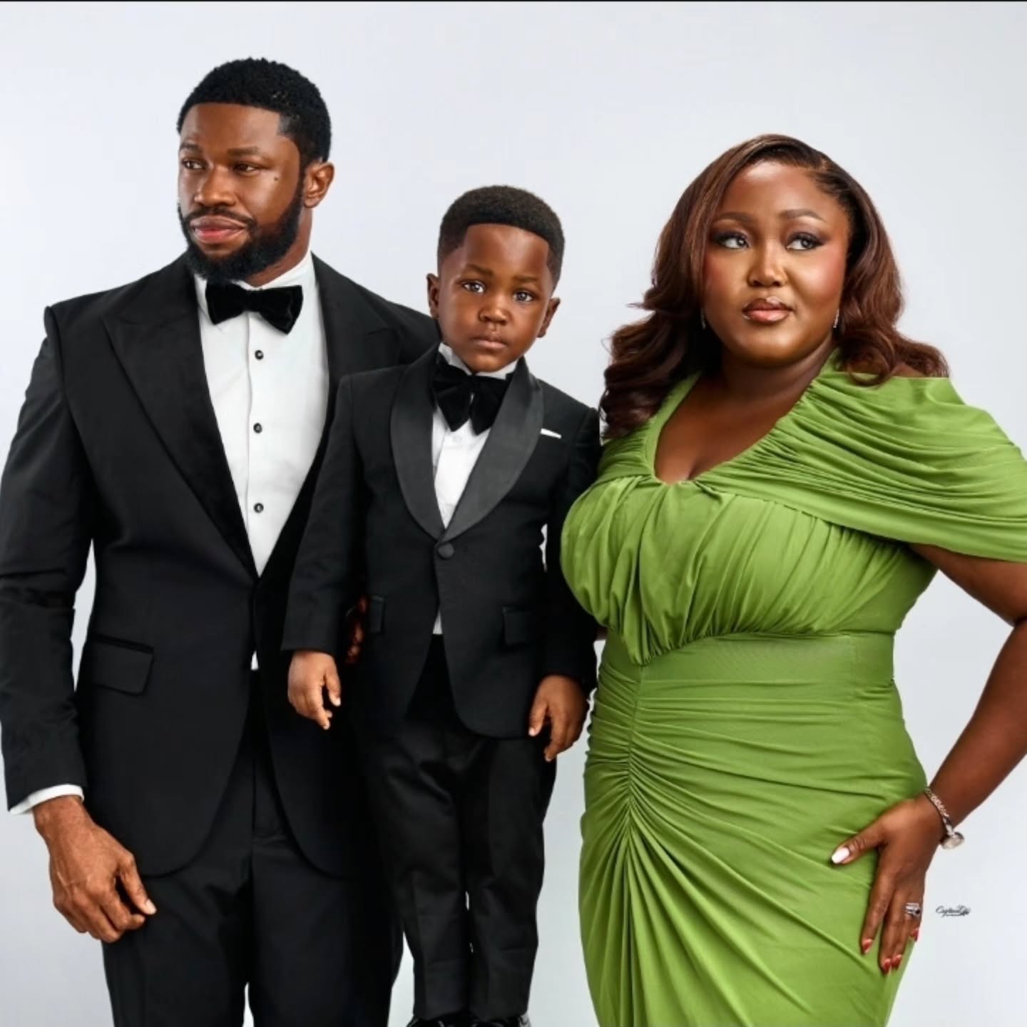 Stan Nze, Jayden, and Blessing Obasi posing in black tuxedos and a green dress for Jayden’s 3rd birthday.