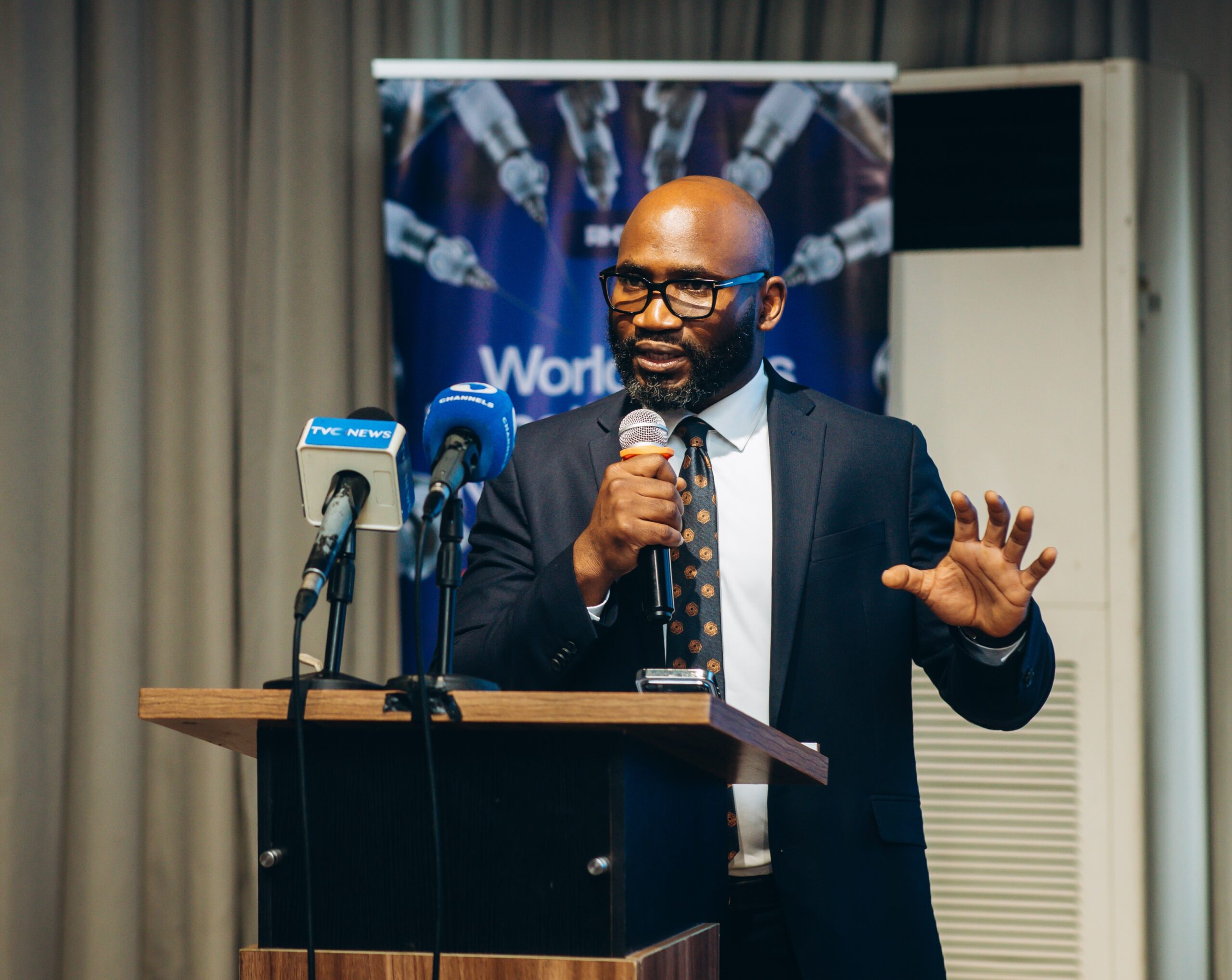 Professor Obi Davies-Ekwenna speaking at podium during Redeemer’s Health Village Robotics Surgery Launch Dinner following West Africa’s first tele-robotic surgery.