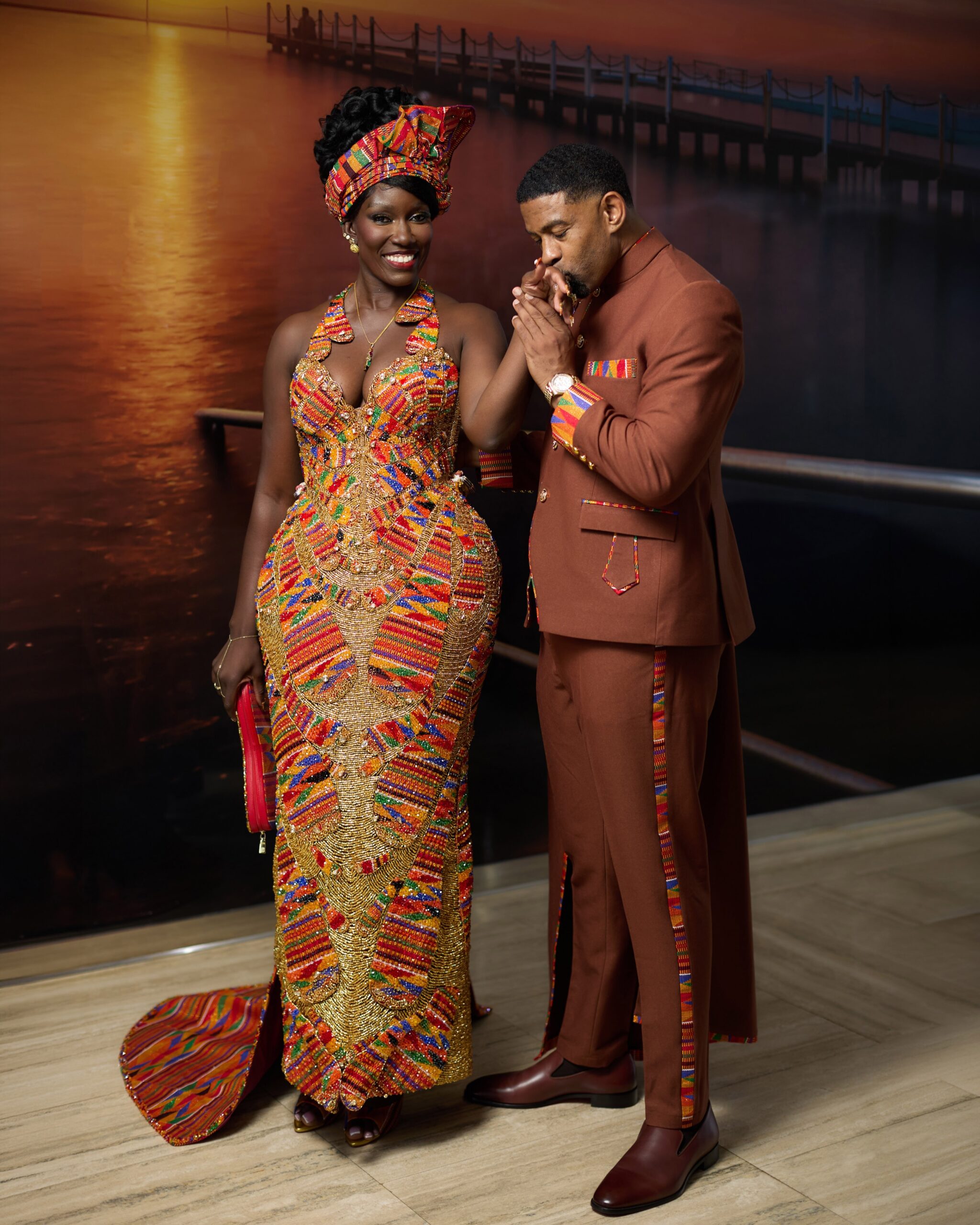 Keely Watson kissing the hand of Bozoma Saint John, who wears a corseted halter-neck Kente gown by Mimmy Yeboah.