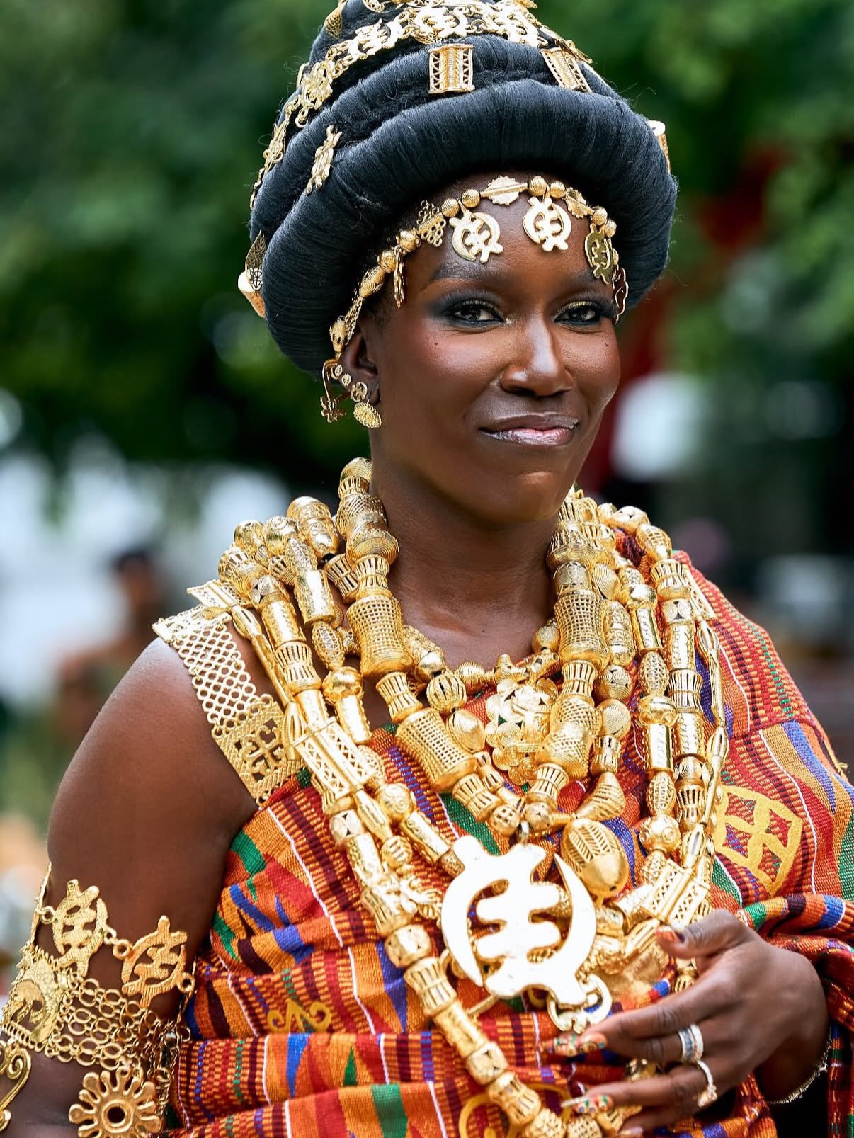 Bozoma Saint John wearing traditional Akan gold beaded necklaces, arm cuffs, Tikua headpiece, and hand-woven Kente drape.