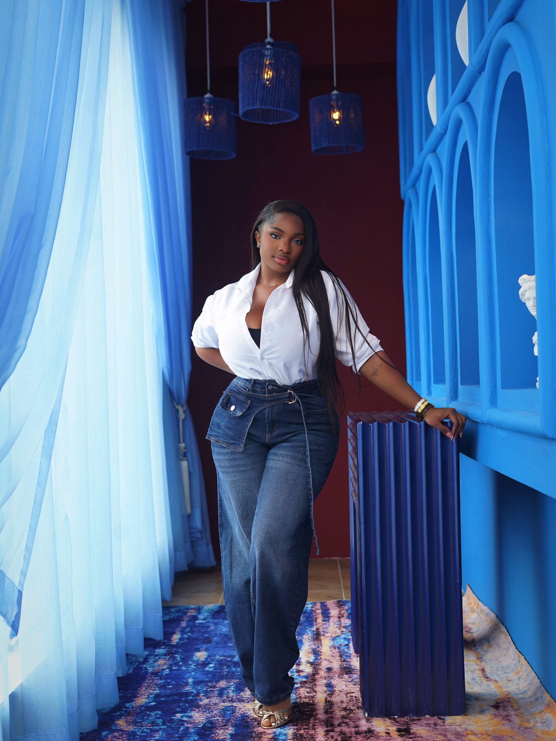 Dorathy Bachor wearing a white button-down shirt with high-waisted dark-wash wide-leg jeans and gold heels