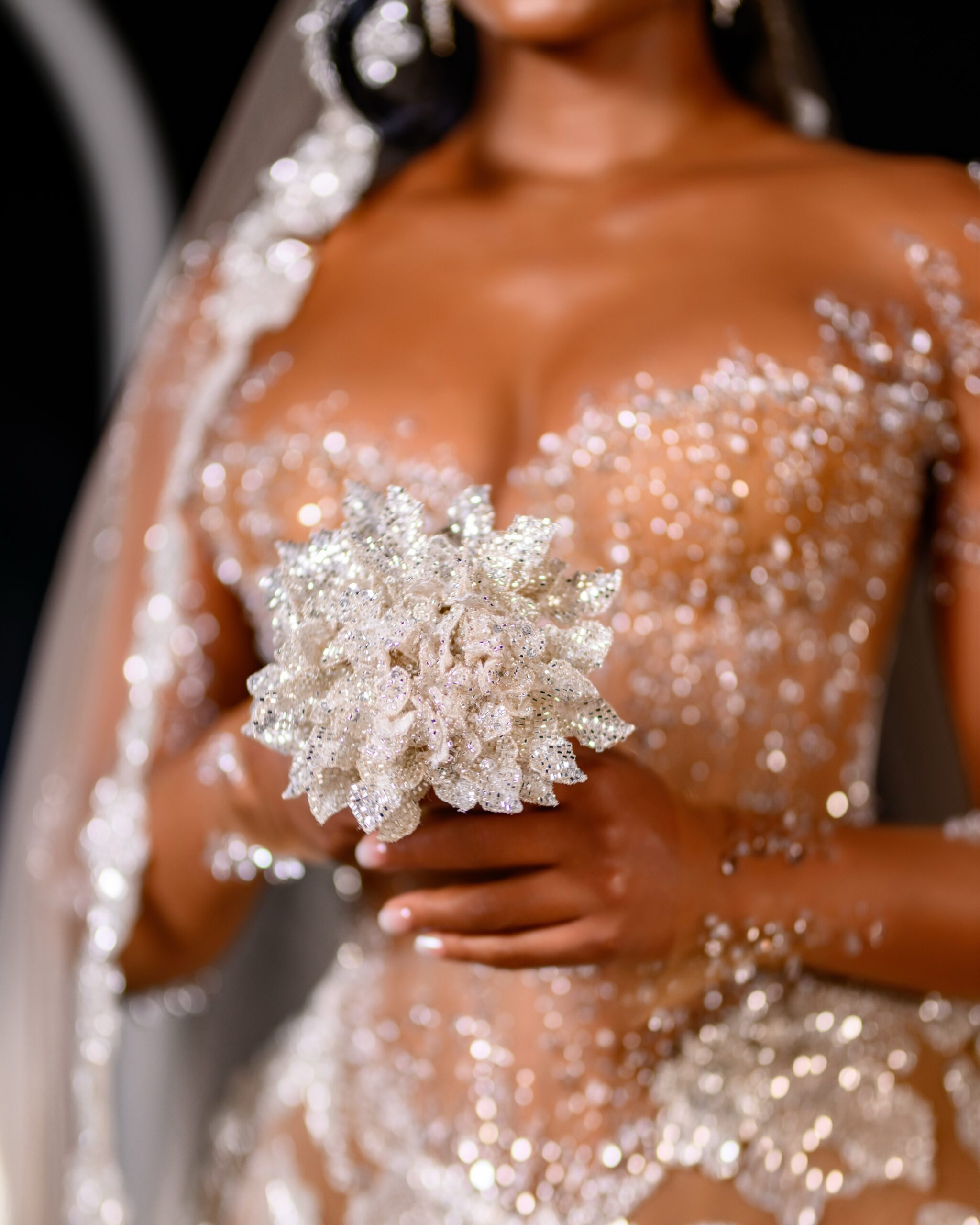 Osas Ighodaro holding a beaded silver bridal bouquet wearing a sheer crystal corseted gown