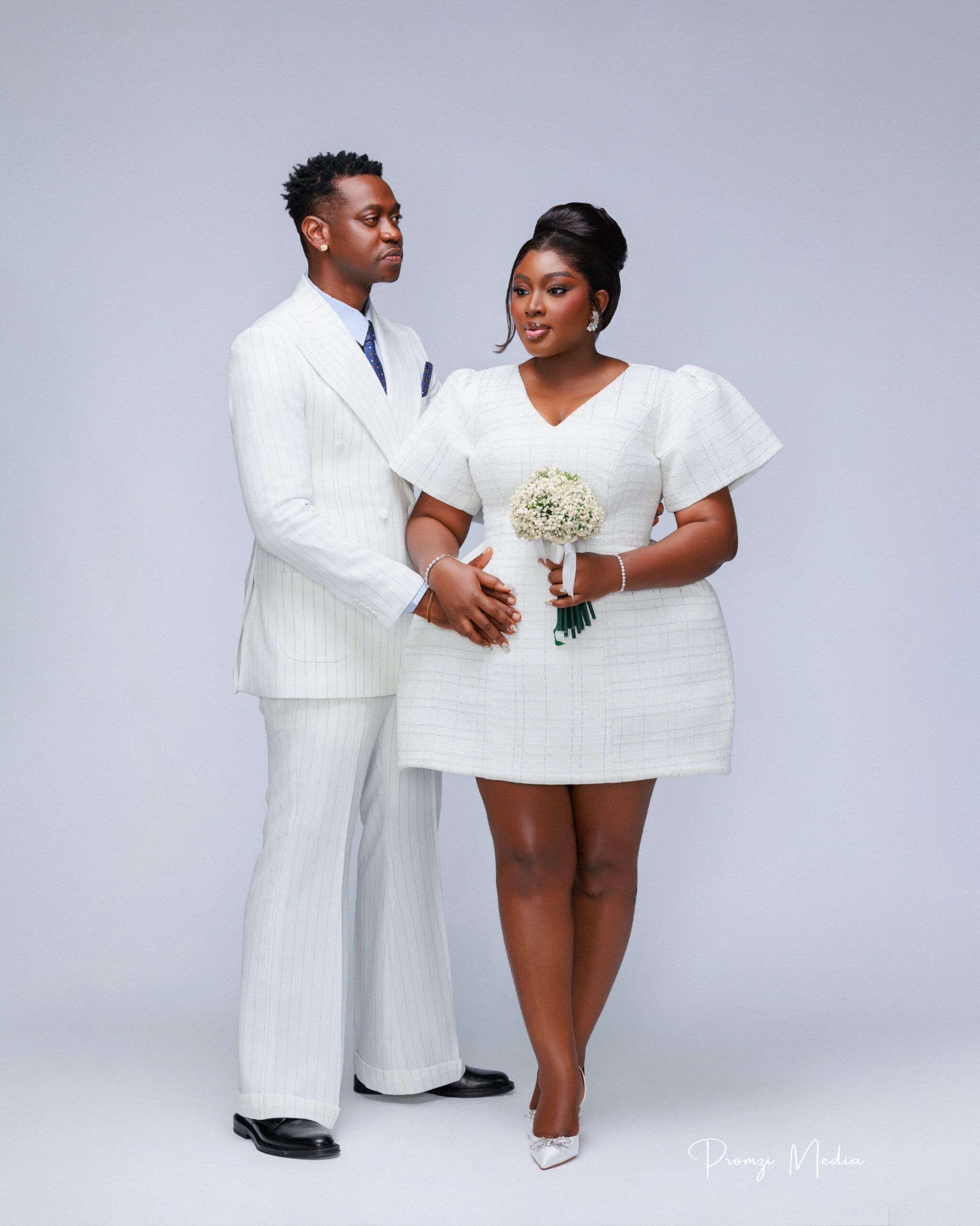 Mo Bimpe holding a white floral bouquet in a structured bell mini dress with Lateef Adedimeji
