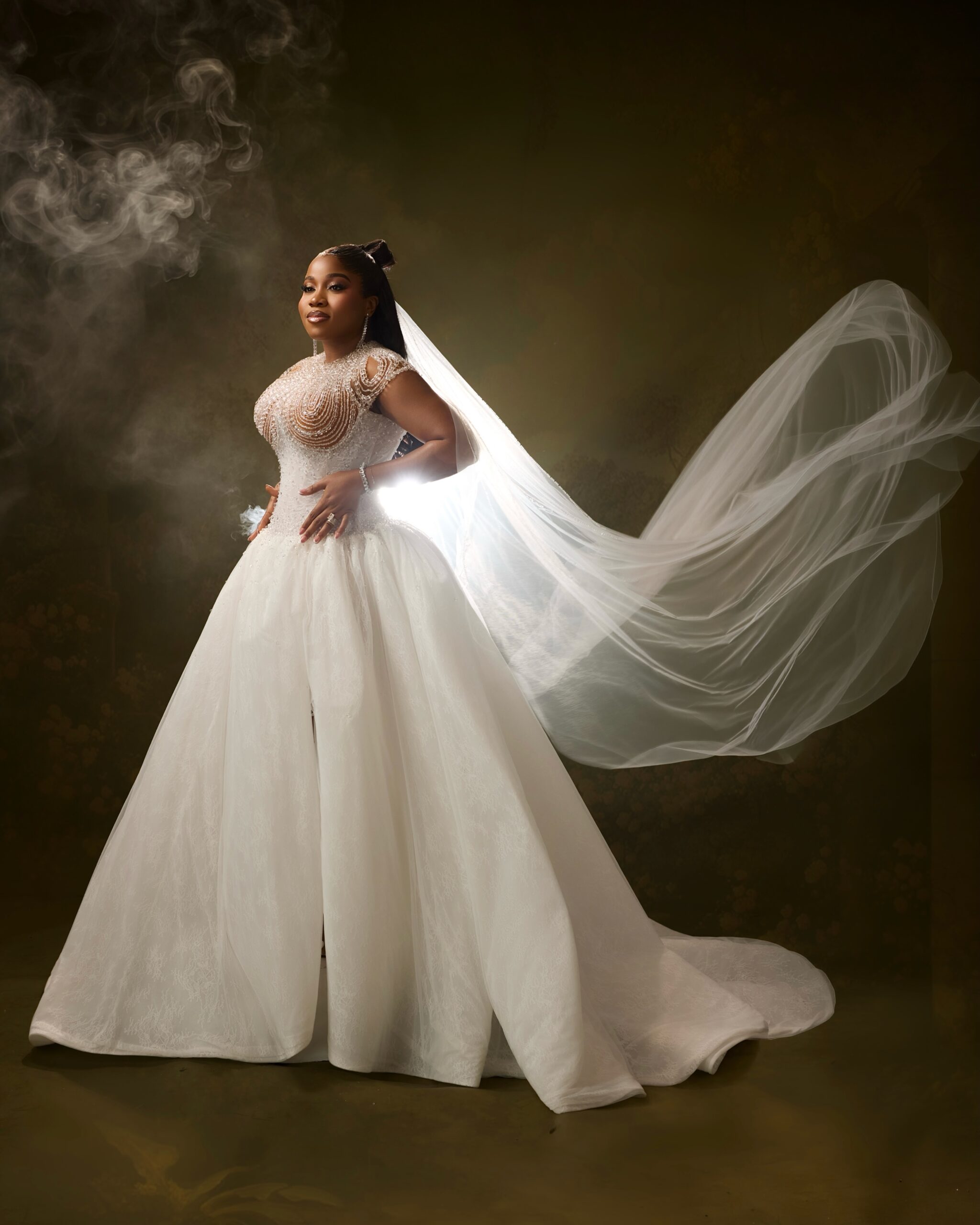 Veekee James posing in a custom white ballgown with a long billowing tulle veil