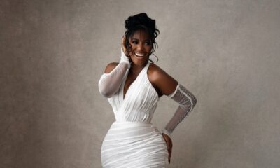 Hilda Baci smiling in a white pleated halterneck gown with pearl gloves and a vintage updo at A Mama Deola Wedding Story premiere.