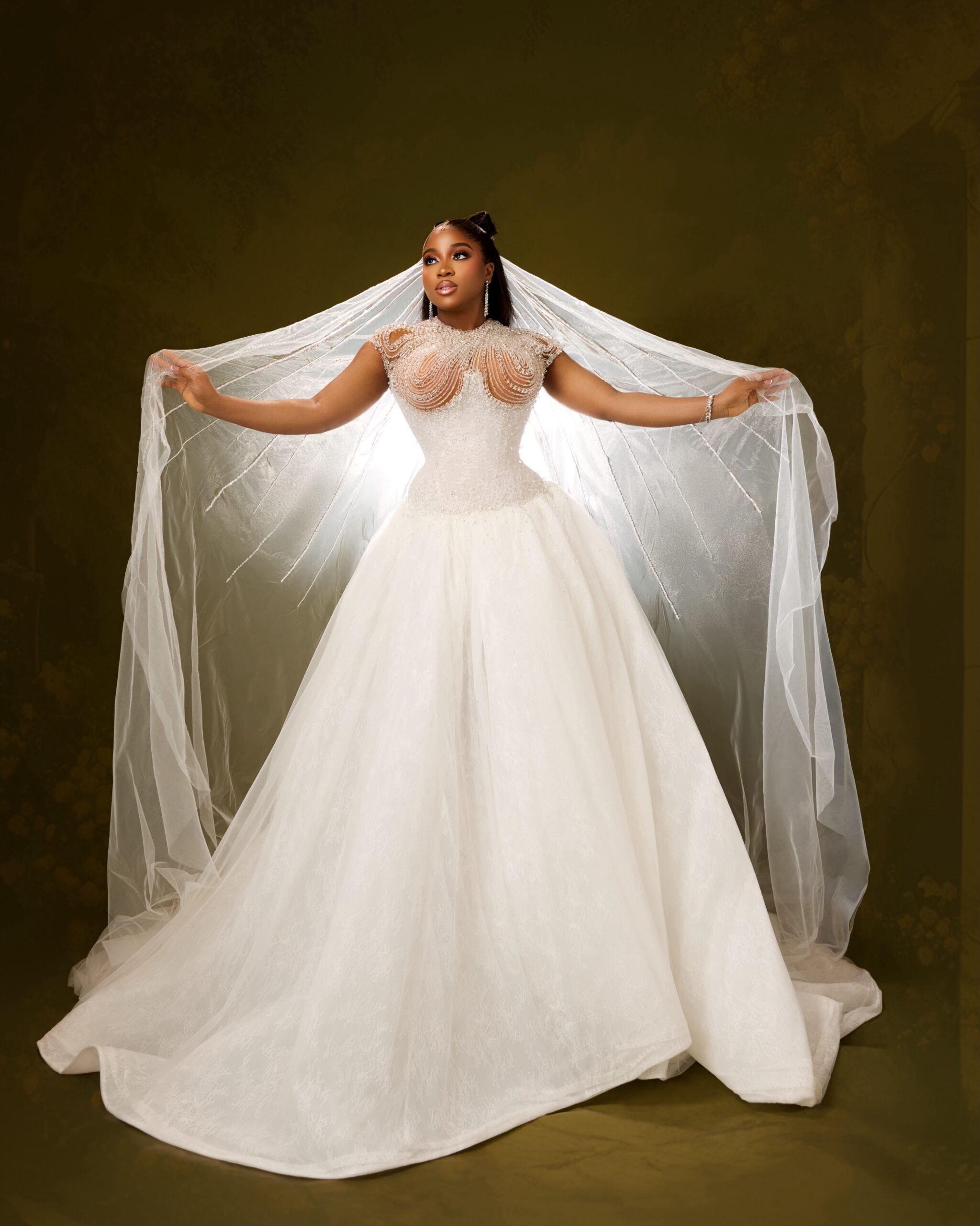 Veekee James holding out a wide tulle veil in a white corset ballgown
