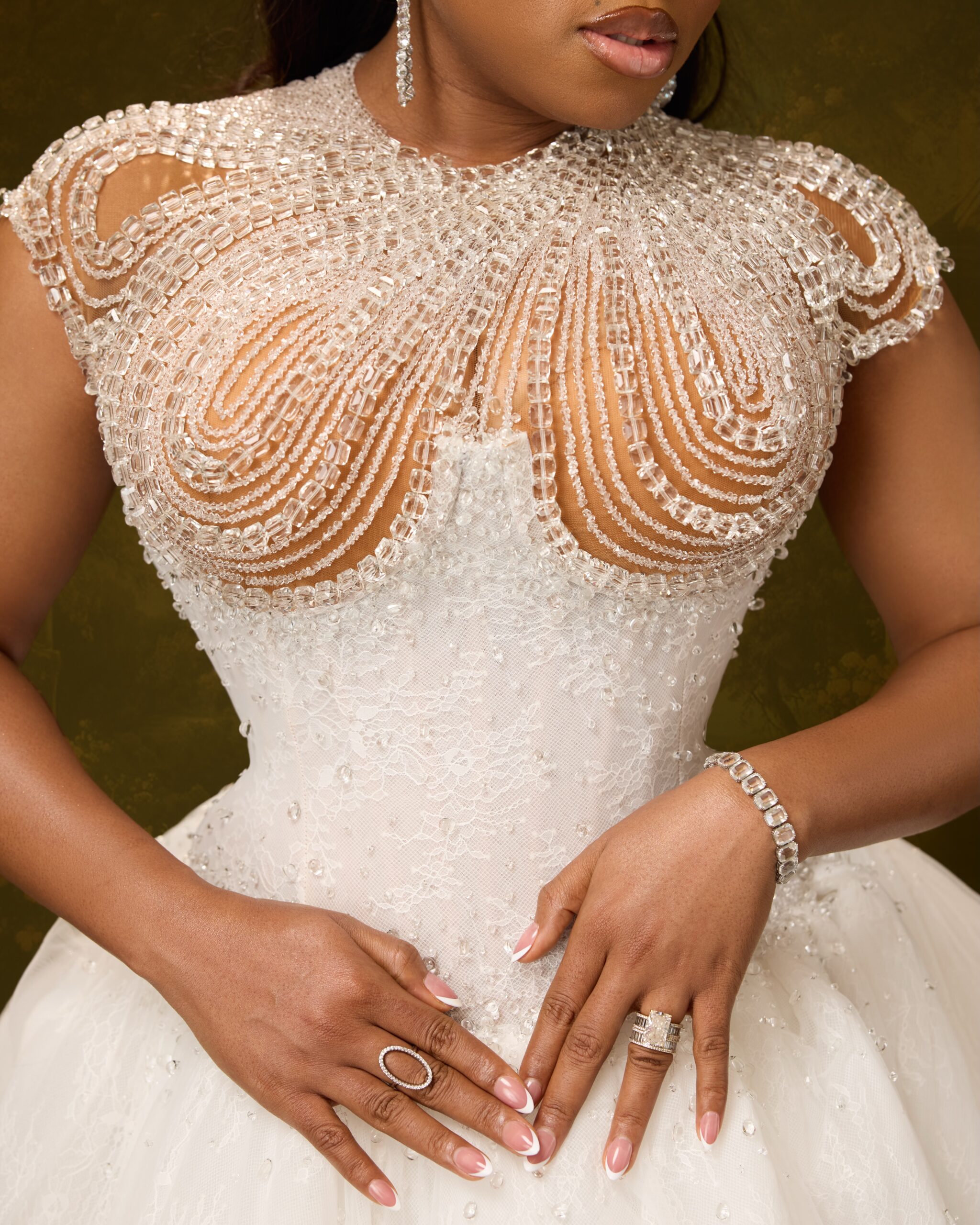 Swirling crystal beadwork on a sheer bodice with a diamond wedding ring and tennis bracelet