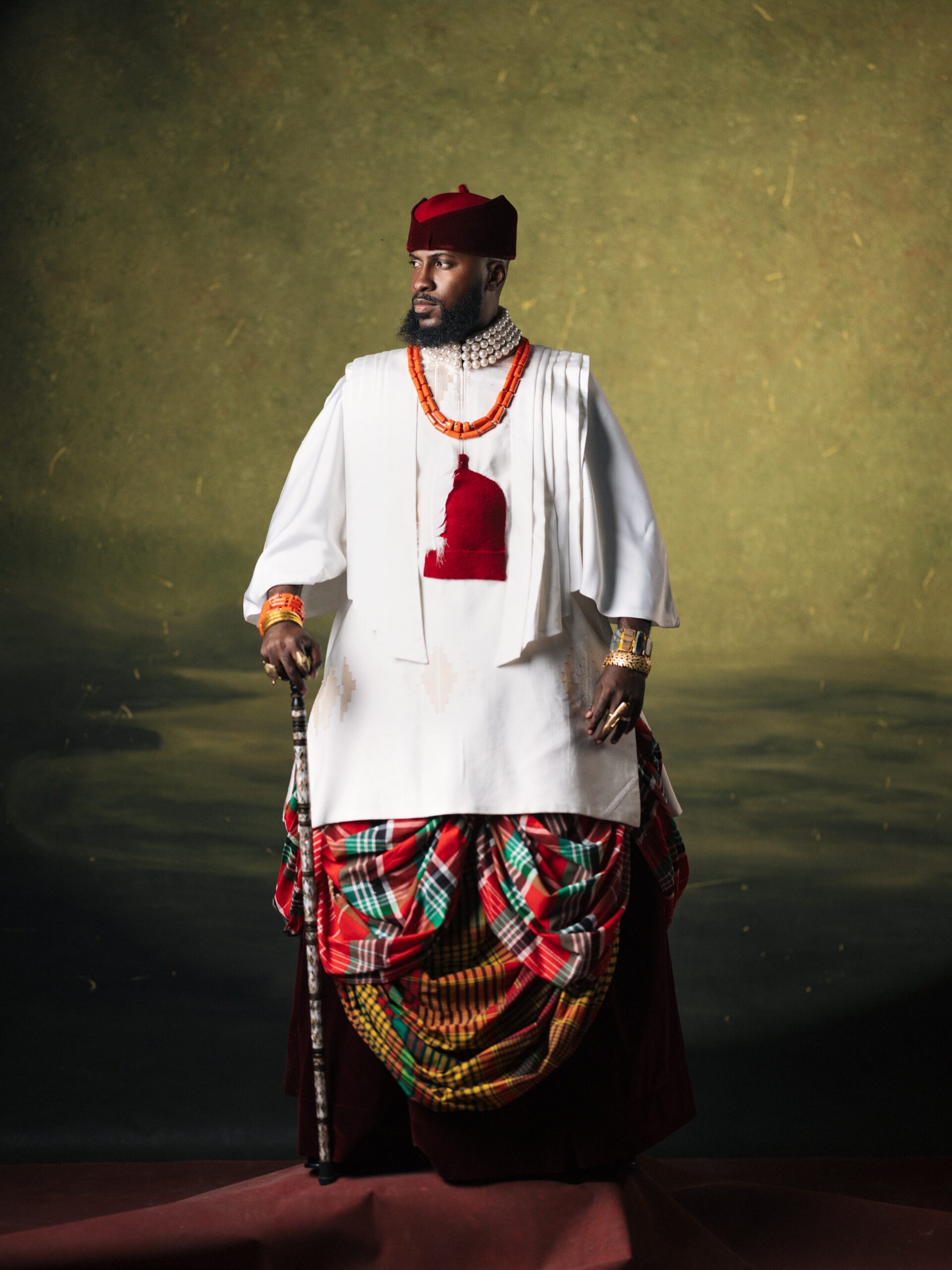 Dr Akin Faminu in a white Deji & Kola tunic, red and green tartan George skirt, red cap, and pearl necklace.