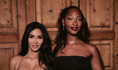Tems in a black strapless dress posing beside Kim Kardashian in a brown leather corset dress at the SKIMS London event.