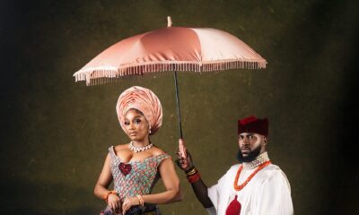 Kiky Festus under a pink parasol next to Akin Faminu in a white tunic and tartan George skirt.