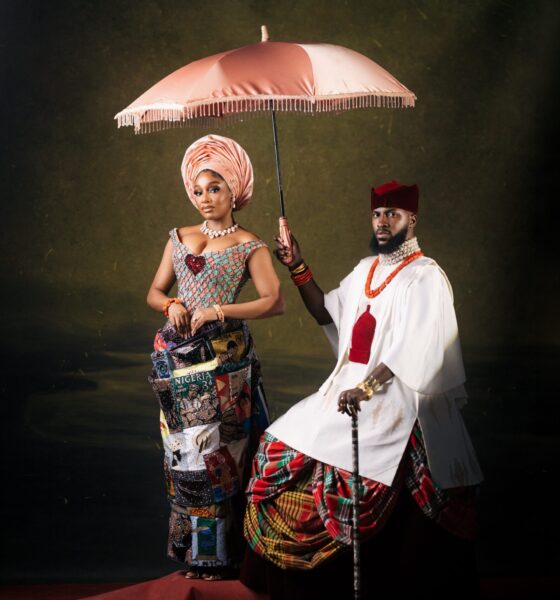 Kiky Festus under a pink parasol next to Akin Faminu in a white tunic and tartan George skirt.