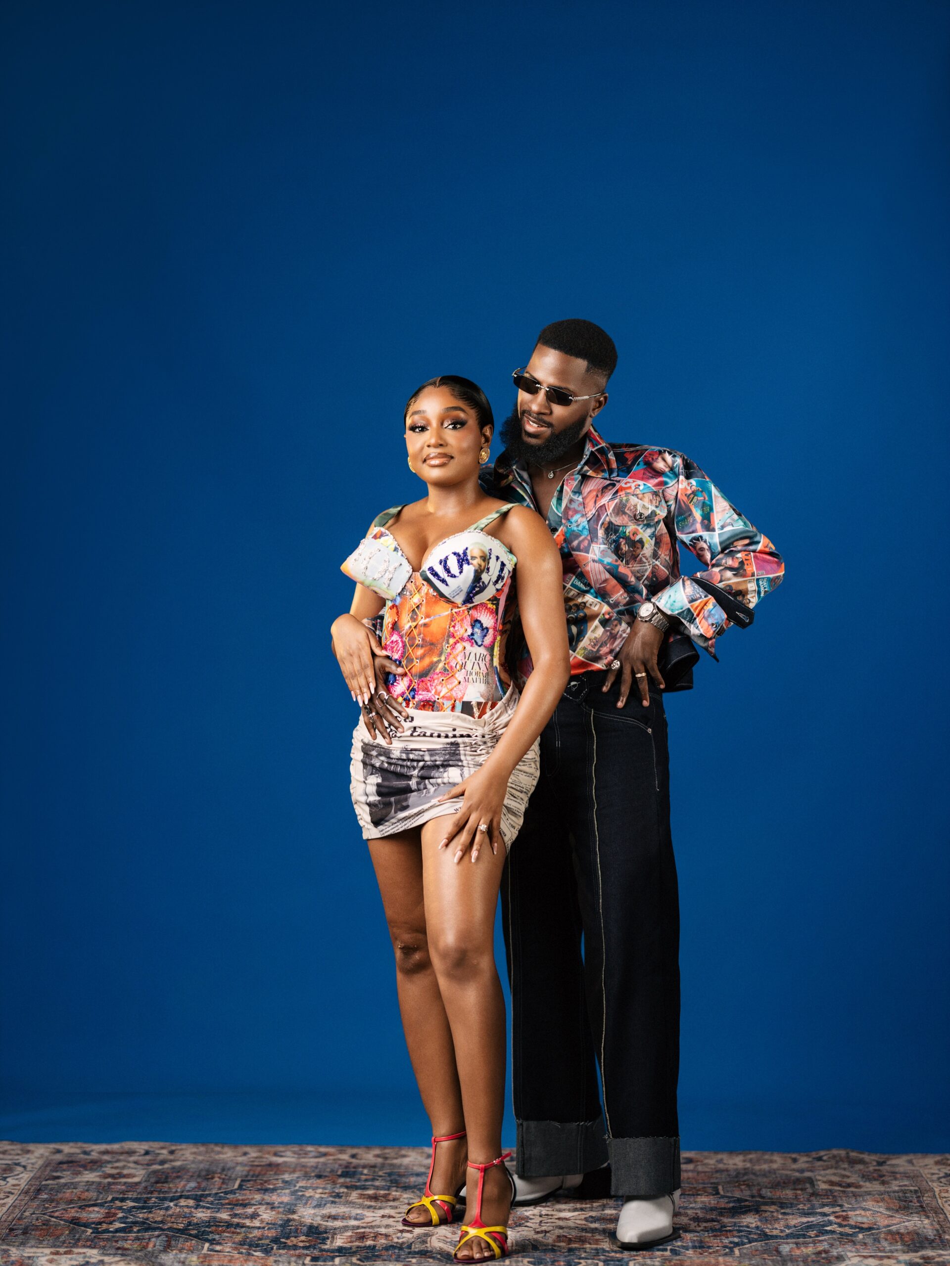 Akin Faminu in a Deji & Kola graphic magazine print shirt and Kiky Festus in an Emagine By Bukola Vogue print mini dress.