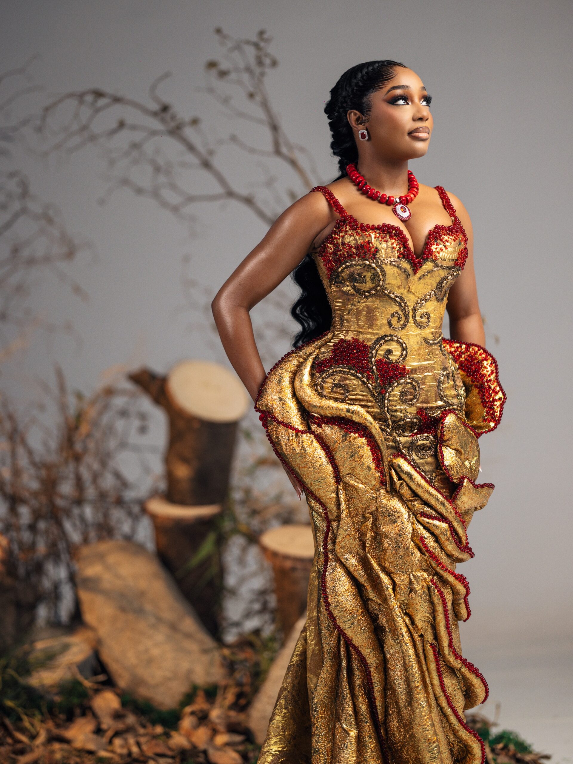 Kiky Festus wearing a metallic gold corseted gown with ruby red beadwork by Emagine By Bukola.