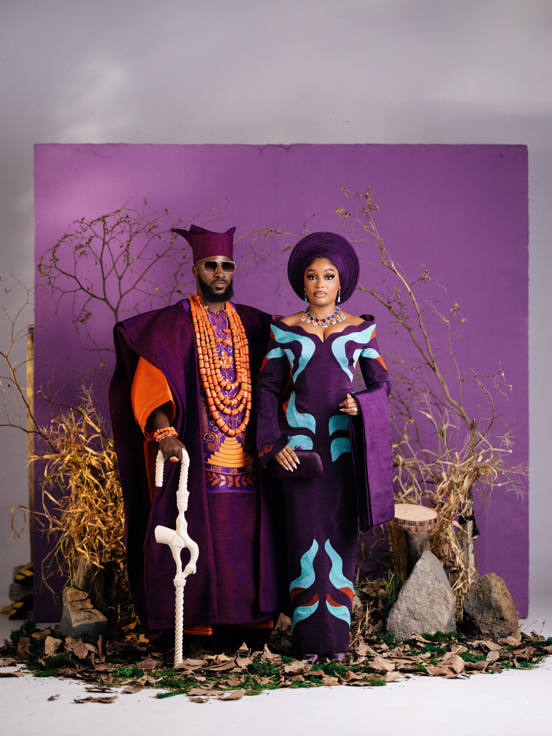 Akin Faminu in a royal purple Ugo Monye agbada and Kiky Festus in a purple Prudential dress posing together.
